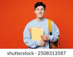 Young smiling happy smart fun cool man student he wearing blue casual clothes backpack bag holding books looking camera isolated on plain red orange background. High school university college concept