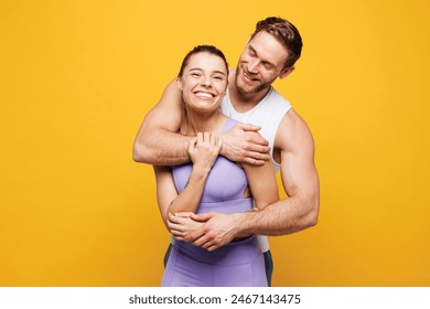 Young smiling happy strong fitness trainer instructor sporty two man woman wear blue clothes spend time in home gym hug embrace cuddle isolated on plain yellow background. Workout sport fit concept - Powered by Shutterstock