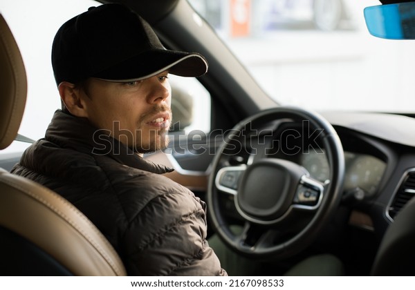 Young smiling happy taxi driver assistant\
caucasian European male in a premium luxury car photo banner\
holding steering wheel.