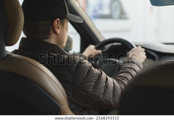 Young smiling happy taxi driver assistant\
caucasian European male in a premium luxury car photo banner\
holding steering wheel.