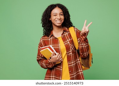 Young smiling happy teen girl student wears brown yellow casual clothes backpack bag hold books showing victory sign isolated on plain green color background. High school university college concept - Powered by Shutterstock