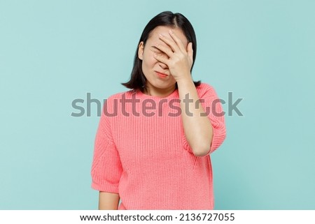 Young smiling happy woman of Asian ethnicity 20s wearing pink sweater put hand on face facepalm epic fail mistaken omg gesture isolated on pastel plain light blue color background studio portrait. Foto d'archivio © 