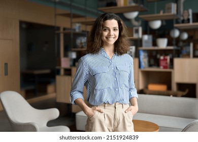 Young smiling latin girl college student teacher looking at camera standing in university campus  Happy hispanic millennial woman professional posing in modern coworking creative office space 