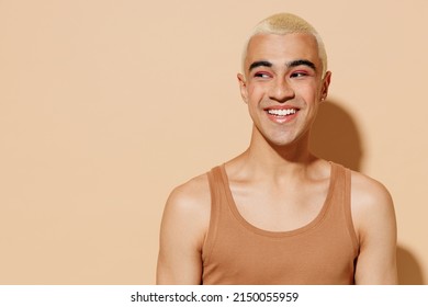 Young Smiling Laughing Cheerful Blond Latin American Gay Man 20s With Make Up In Beige Tank Shirt Looking Aside Isolated On Plain Light Ocher Background Studio Portrait People Lgbt Lifestyle Concept.