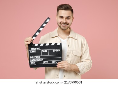 Young Smiling Laughing Cheerful Fun Man 20s Wear Jacket White T-shirt Holding Classic Black Film Making Clapperboard Isolated On Pastel Pink Color Background Studio Portrait. Lifestyle People Concept