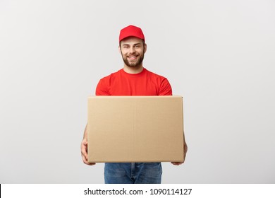 Young smiling logistic delivery man in red uniform holding the box on white background