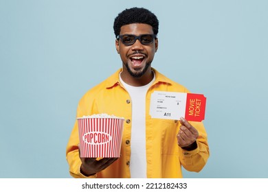 Young Smiling Man Of African American Ethnicity In 3d Glasses Watch Movie Film Hold Bucket Of Popcorn Ticket Look Camera Isolated On Plain Blue Background People Emotions In Cinema Lifestyle Concept