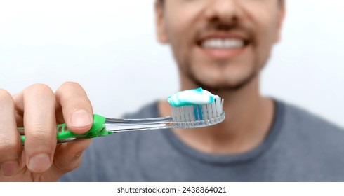 Young smiling man brushing his teeth. Oral hygiene with toothbrush and toothpaste. World Oral Health Day. Cleaning and brushing teeth with fluoride. - Powered by Shutterstock
