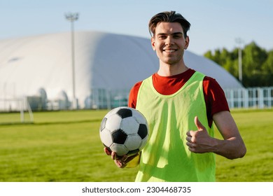 Young smiling man football player holding soccer ball with thumb up, copy space - Powered by Shutterstock