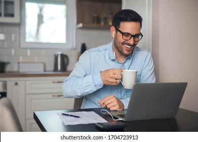 A young smiling man having a video call on laptop while wearing headphones and drinks coffee. - Powered by Shutterstock