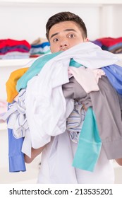 Young Smiling Man Holding Laundry. Portrait Of Young Man Carrying Dirty Clothes