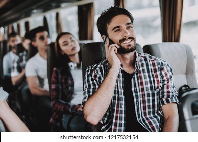 Young Smiling Man Talking On Phone In Tourist Bus. Young Handsome Man Sitting On Passenger Seat Of Tour Bus And Having Phone Call. Traveling, Tourism And People Concept. Happy Travelers On Trip