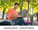 Young smiling man using a laptop computer outdoors