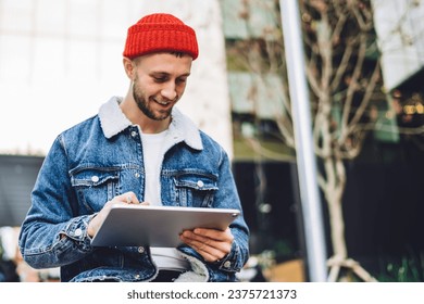 Young smiling man using tablet with stylus outside - Powered by Shutterstock