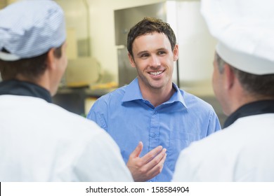 Young smiling manager talking to the staff standing in a kitchen - Powered by Shutterstock