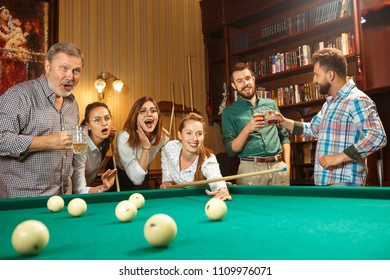 Young smiling men and women playing billiards at office or home after work. Business colleagues involving in recreational activity. Friendship, leisure activity, game concept. Human emotions concepts - Shutterstock ID 1109976071