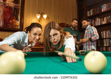 Young smiling men and women playing billiards at office or home after work. Business colleagues involving in recreational activity. Friendship, leisure activity, game concept. Human emotions concepts - Shutterstock ID 1109976101