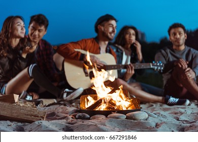 young smiling multiethnic friends spending time near campfire - Powered by Shutterstock