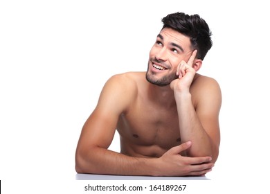 young smiling naked beauty man is looking up to his side on white background