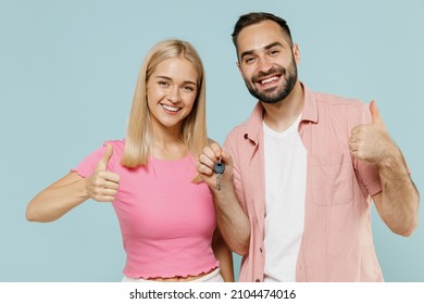 Young Smiling Overjoyed Couple Two Friends Family Man Woman In Casual Clothes Together Holding Apartment House Home Keys Show Thumb Up Gesture Isolated On Pastel Plain Light Blue Background Studio.