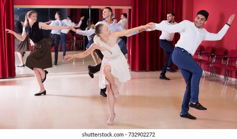 Young smiling people practicing vigorous lindy hop movements in dance class