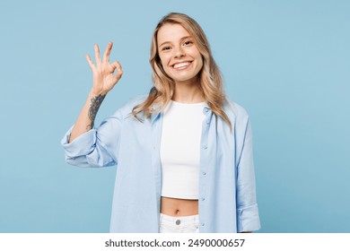 Young smiling positive satisfied happy woman she wearing white top shirt casual clothes showing okay ok gesture isolated on plain pastel light blue cyan background studio portrait. Lifestyle concept - Powered by Shutterstock