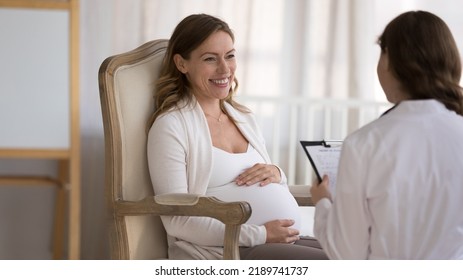 Young Smiling Pregnant Woman Patient Answers Questions Of Gynecologist During Visit At Home. Ob-gyn Asks About Health In Late Stages Of Pregnancy, Filling Medical Form, Provide Prenatal Care Concept