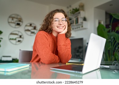 Young smiling pretty business woman student sitting at table at home office with laptop computer looking at camera advertising elearning online course, remote work, business webinar. Portrait. - Powered by Shutterstock