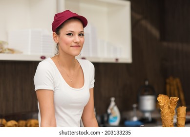 Young Smiling Saleswoman Portrait Inside Ice Cream Shop.