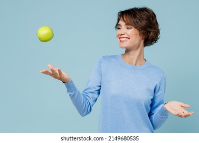 Young smiling satisfied happy vegetarian cool woman 20s in casual sweater look camera toss up green apple isolated on plain pastel light blue background studio portrait. People lifestyle food concept. - Shutterstock ID 2149680535