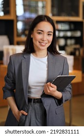 Young smiling successful professional leader Asian business woman, female executive manager, saleswoman wearing suit holding digital tablet standing in office looking at camera, vertical portrait. - Shutterstock ID 2192831111