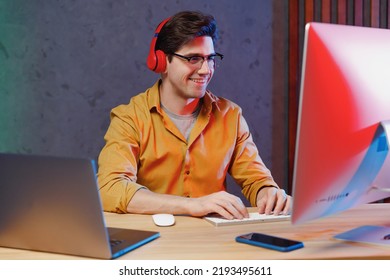 Young smiling video content creator man in shirt headphones listen to music work at home sharing new production for his channel on laptop pc desktop computer, mounting content. Social media concept - Powered by Shutterstock