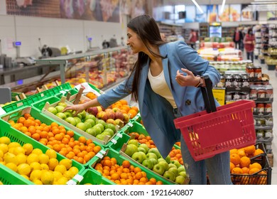 A young smiling womam is buying fruits in the supermarket. - Powered by Shutterstock