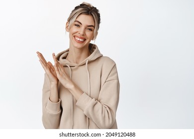 Young Smiling Woman Applause You, Looking Happy And Clapping Hands, Congratulating Someone, Standing Over White Background