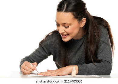 Young Smiling Woman Applying Lacquer Polish, Painting Fingernails With Colorless Protective Enamel, Doing Homemade Manicure In Studio , Close Up View