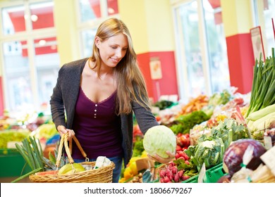 Young Smiling Woman Buys Cabbage And Other Vegetables In Health Food Store