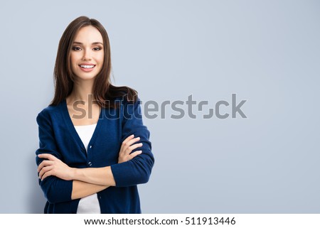 Young smiling woman in casual blue clothing with crossed arms, with copyspace area for advertise text or slogan. Caucasian brunette model in emoshions and optimistic, positive, happy feeling concept. 