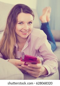 Young smiling woman checking her phone and taking selfies at home