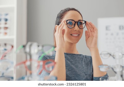 Young smiling woman choosing a new pair of prescription glasses at the eyewear store - Powered by Shutterstock