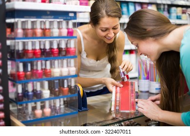 Young Smiling Woman Choosing New Nail Polish Tone At Cosmetic Shop 