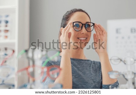 Young smiling woman choosing a new pair of prescription glasses at the eyewear store