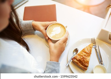 Young Smiling Woman Doing A Coffe Break Sitting In Cafe, With Notebook And Cup Of Coffe Or Latte , Spinach Pie, Overhead View.