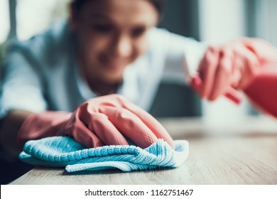 Young Smiling Woman in Gloves Cleaning House. Closeup of Happy Beautiful Girl wearing Protective Gloves Cleaning Desk by spraying Cleaning Products and wiping with Sponge. Woman Cleaning Apartment - Shutterstock ID 1162751467