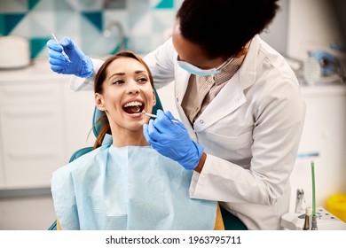 Young smiling woman having her teeth checked by dentist during appointment at dental clinic. - Powered by Shutterstock