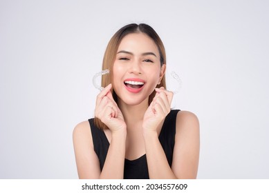 Young smiling woman holding invisalign braces in studio, dental healthcare and Orthodontic concept - Powered by Shutterstock