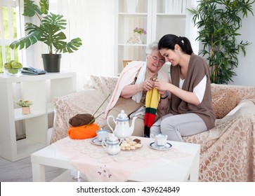 Young Smiling Woman Knitting With A Help Of Her Old Neighbor