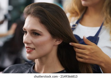 Young smiling woman with long brown hair vising beauty salon to get blowdry