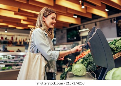 Young smiling woman measuring vegetables and shopping for groceries in the supermarket - Powered by Shutterstock