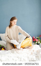 Young Smiling Woman Organizing Clothes Sitting On The Bed At Home