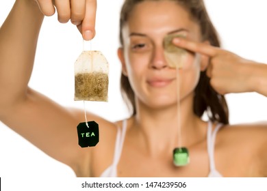 Young Smiling Woman Posing With Tea Bag On Her Eye On White Background